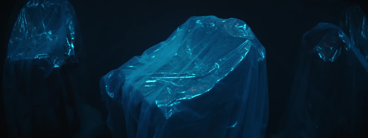 Objects sit wrapped in plastic in a dark room
