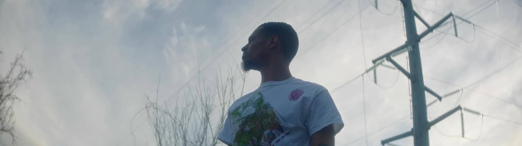A man stands outside near a power line and looks to the left and right
