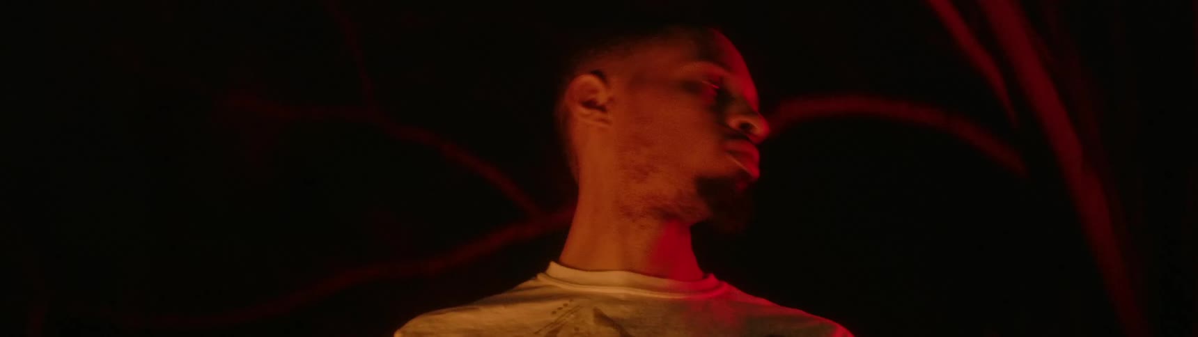 A teenager stands in the dark and moves his head back and forth