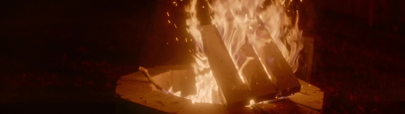 A person walks around a bonfire