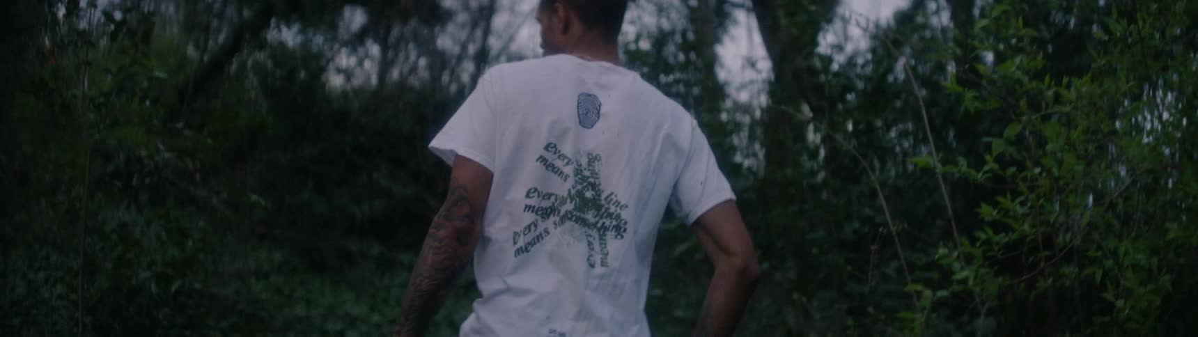 A man hikes through a forest in casual clothing
