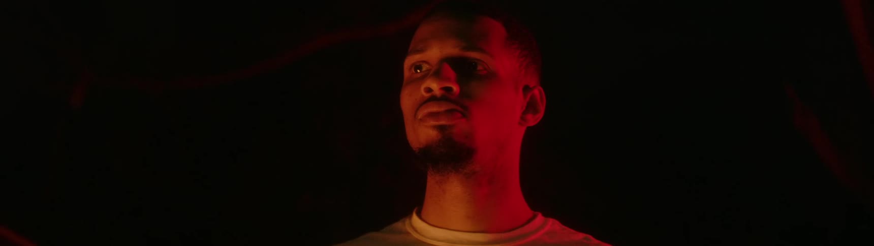 Man against black background cast with red light