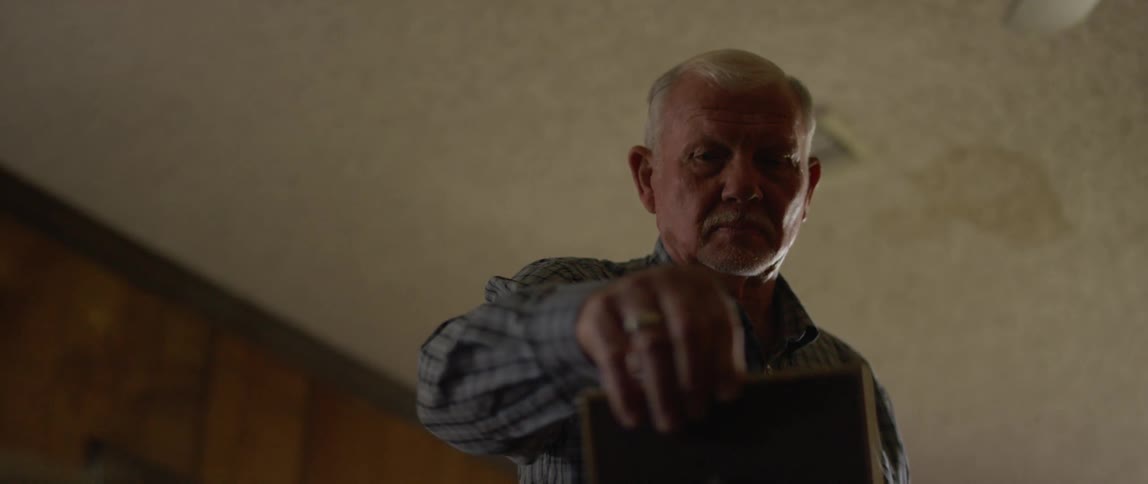 A man straightens a picture frame and then looks at it