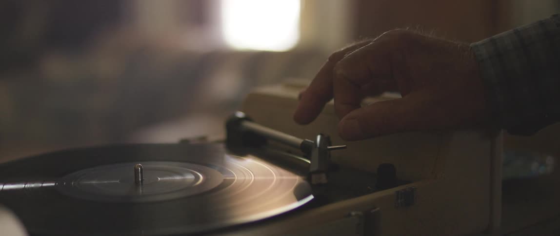 Hand places needle on record spinning on record player