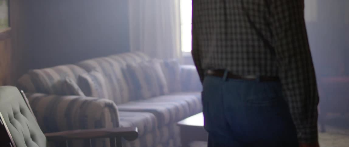 A man walks into his living room filled with old furniture