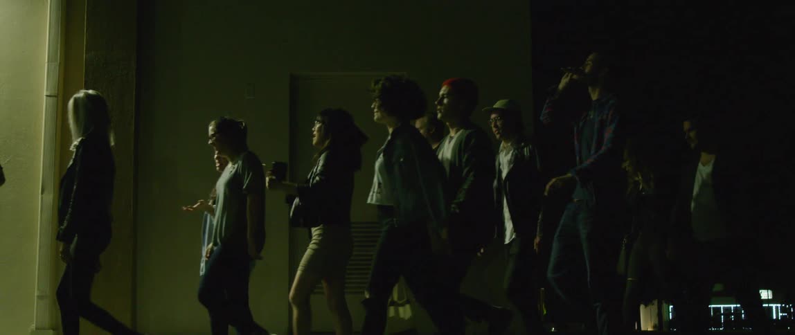 A large group of people walk down a sidewalk