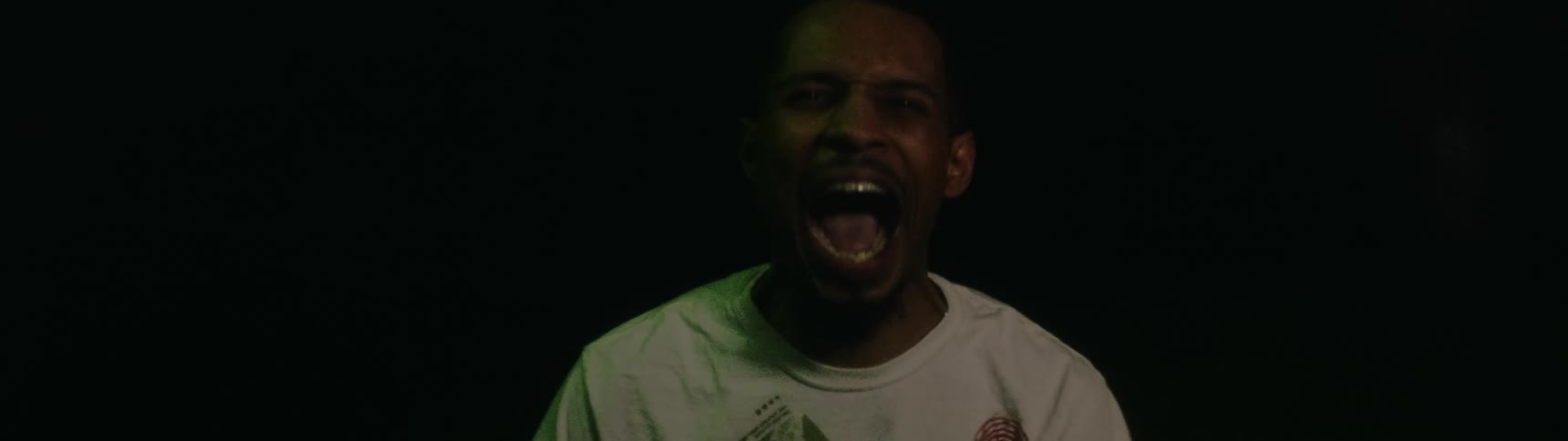 A black man screams while lights flash on him