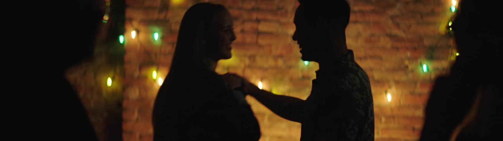 A man and a woman dance in a bar while other patrons look on
