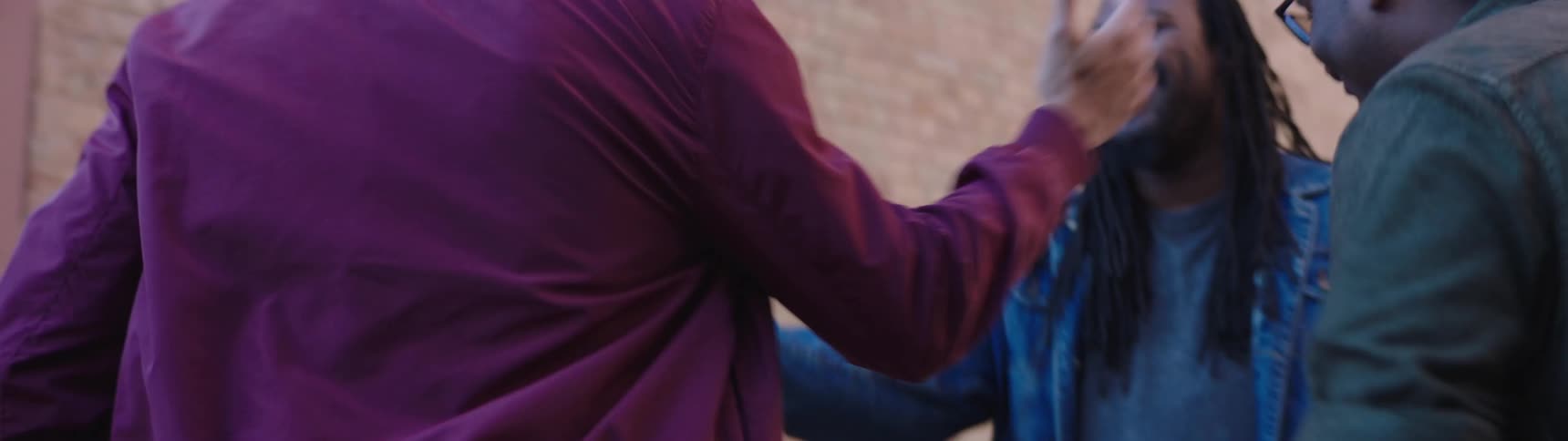 A man sees his friends and hugs and high fives them on the street