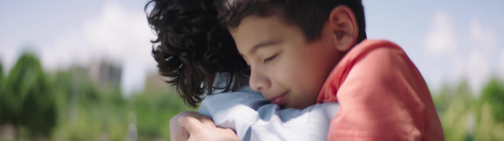 Father and son cuddle affectionately in the public park