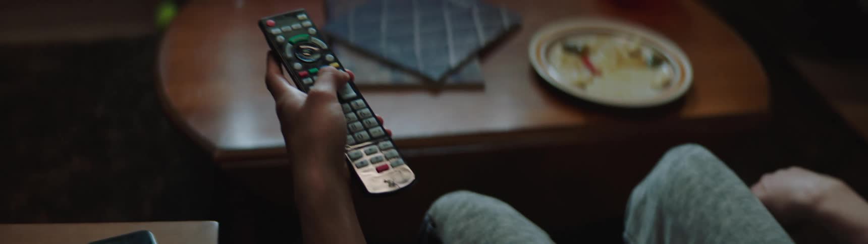 A man uses a remote control while sitting and watching television
