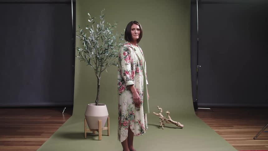 A woman stand in front of screen posing as a model