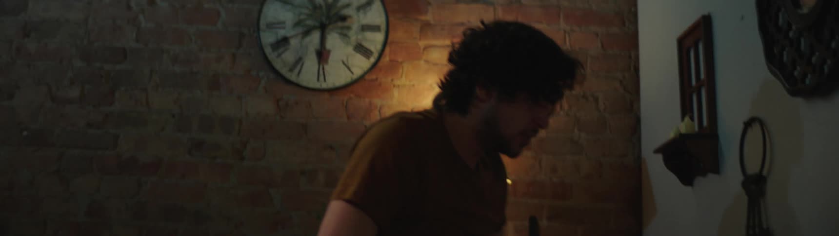 A young man throws tables and lamps in a room as a woman sits there
