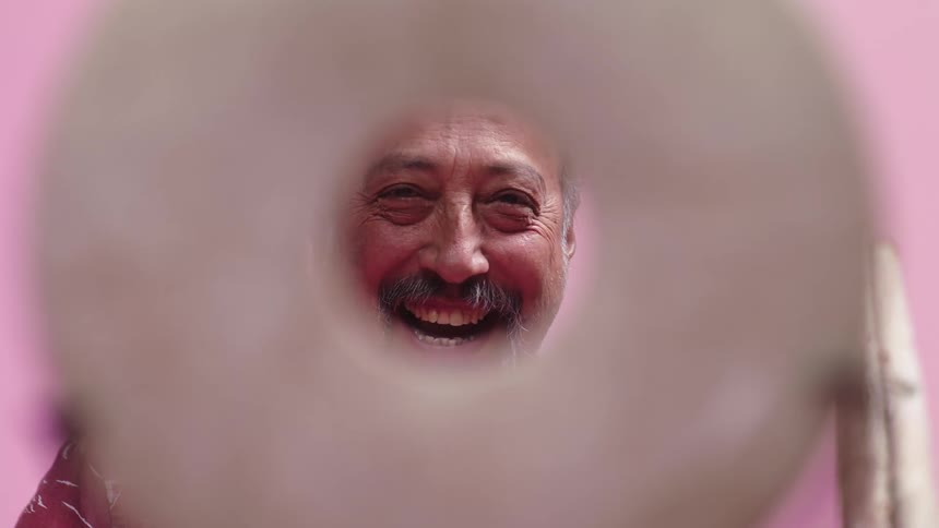 A mans face seen through a hole laughs