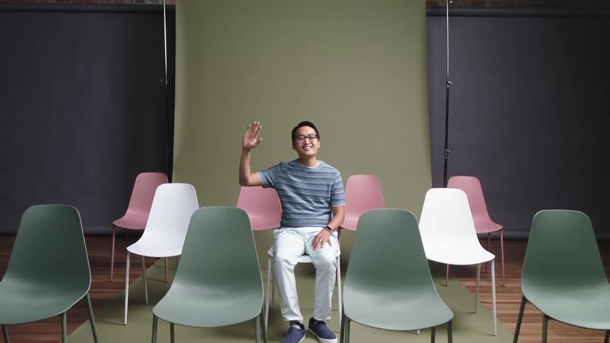 Man sitting in chair smiles and waves