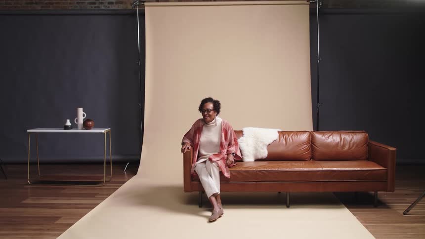 An elderly black woman poses for a photo shoot at an indoor studio