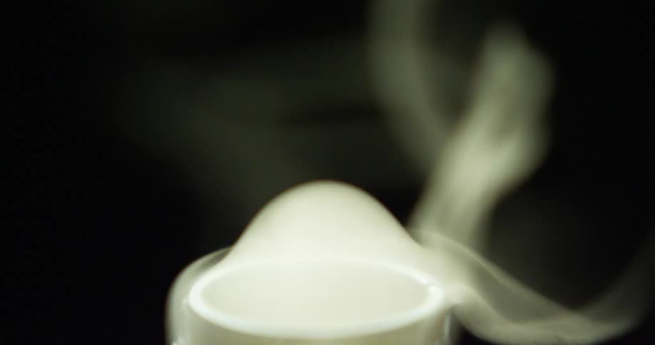 Thick smoke pours out of the opening of a metal tube