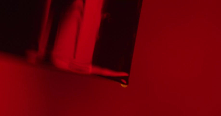 A thick liquid runs down a surface and drips out of the corner