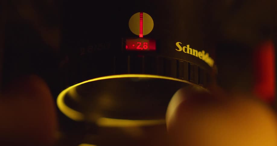 A white male changes the setting on a camera lens