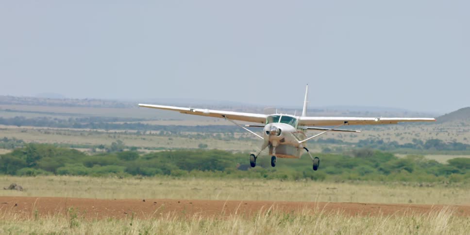 A small plane takes off from a small dirt runway