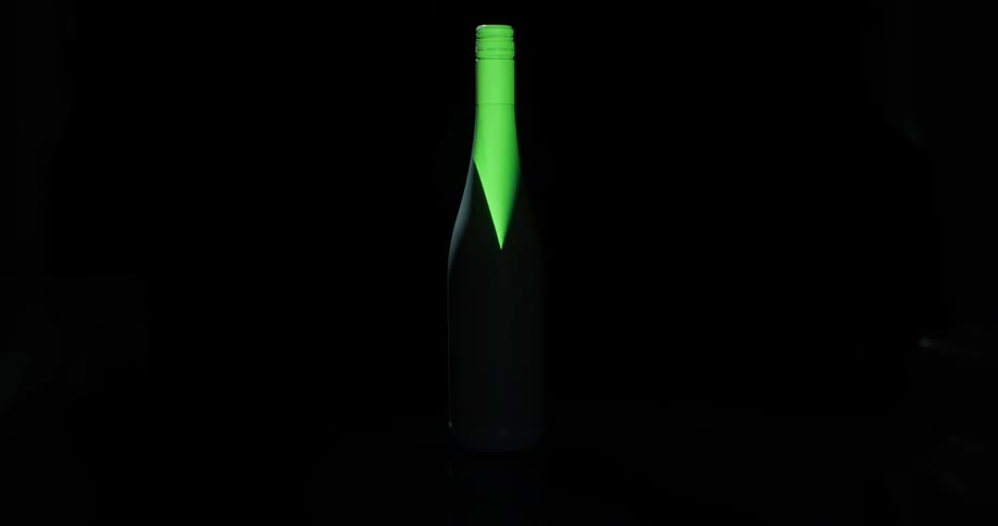 A white bottle with a green rotating light projected on it