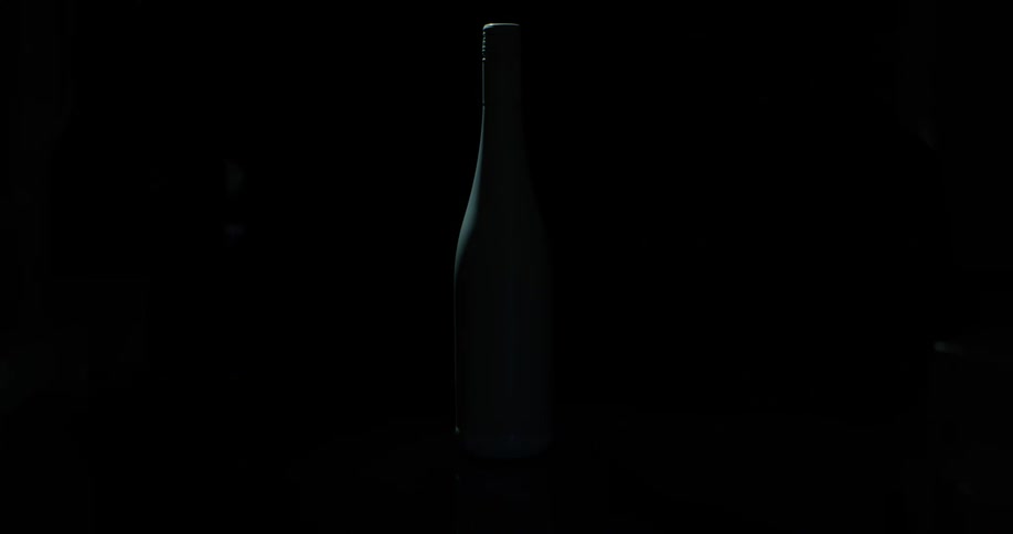 Triangles of light reflect off of a dark wine bottle