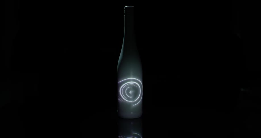 A spinning light is projected onto a white bottle
