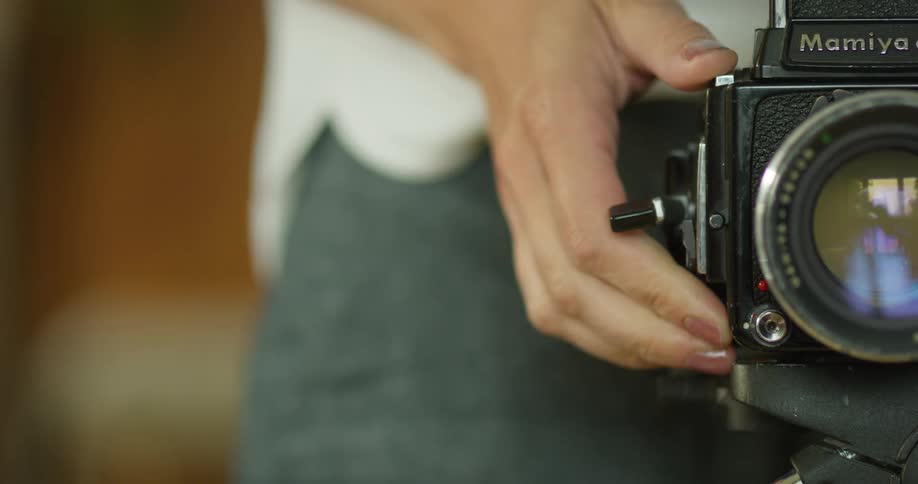 A white person turns a handle on a camera than takes a picture