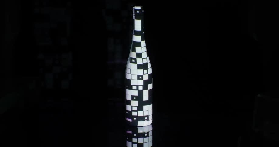 A dark wine bottle covered in different sized squares of light