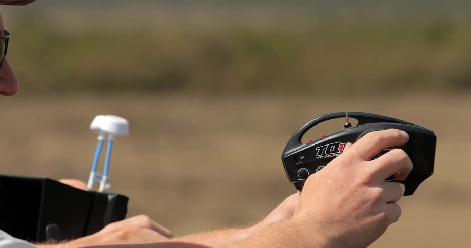 A man holds a controller outside on a sunny day