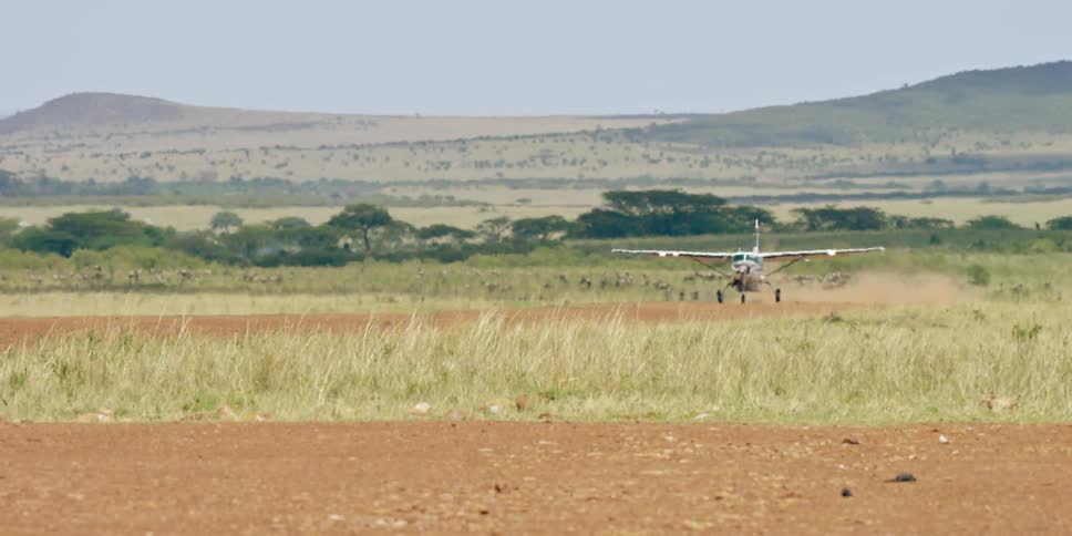 A plane lands on a dirt runway
