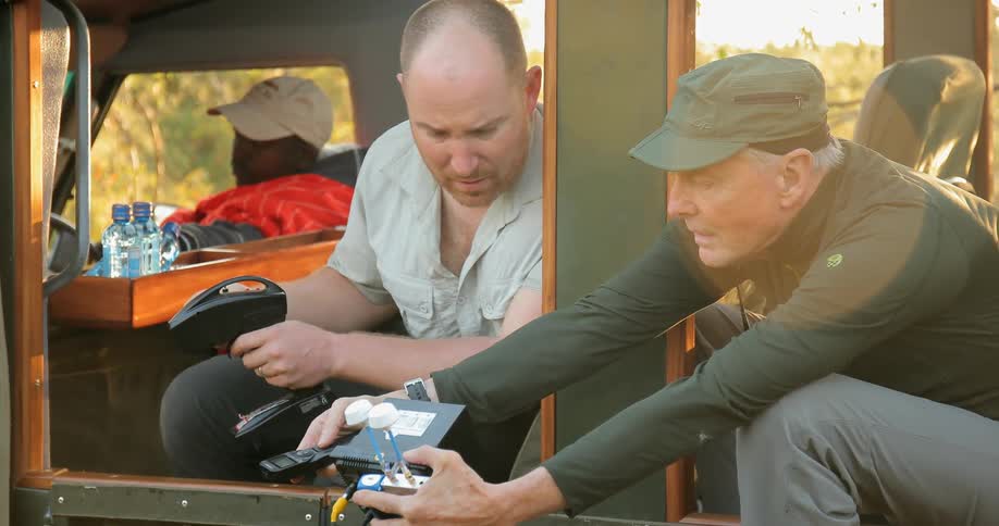 Two men talk and point remotes at something