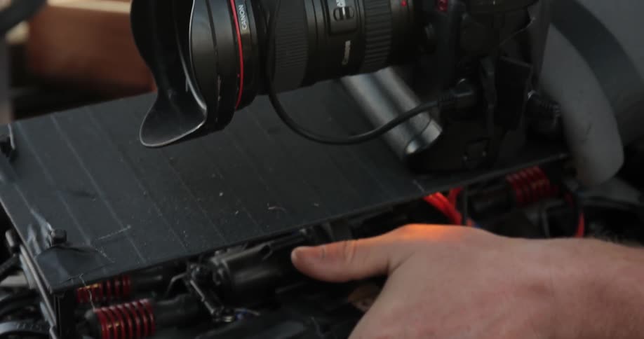 A hand rests below a large camera