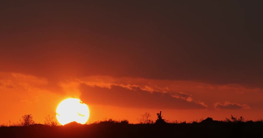 The sun setting behind some clouds