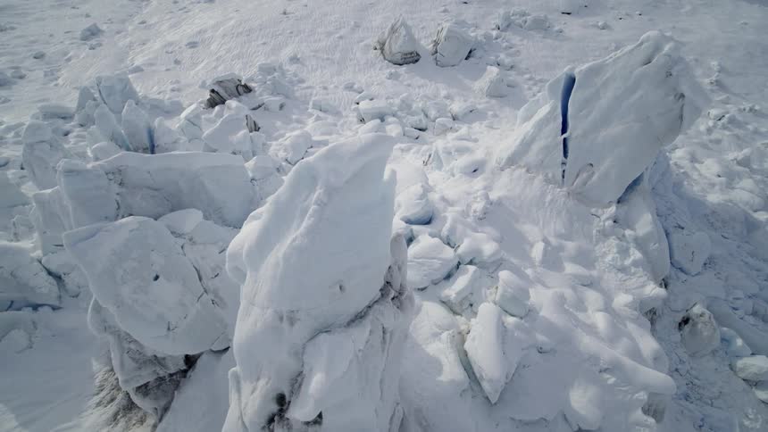 Ice and snow chunks form pile in center of snow covered plain