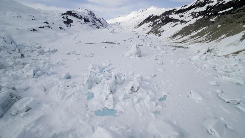Glaciers and tundra with snow and ice with mountains in the background