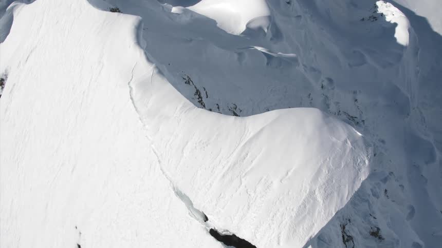 Aerial view of snow and ice formation about to fall from mountain peak