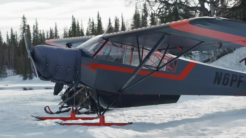 An airplane on snow with trees in the background