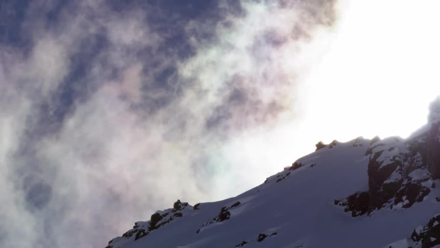 Clouds float over a snow covered mountain peak