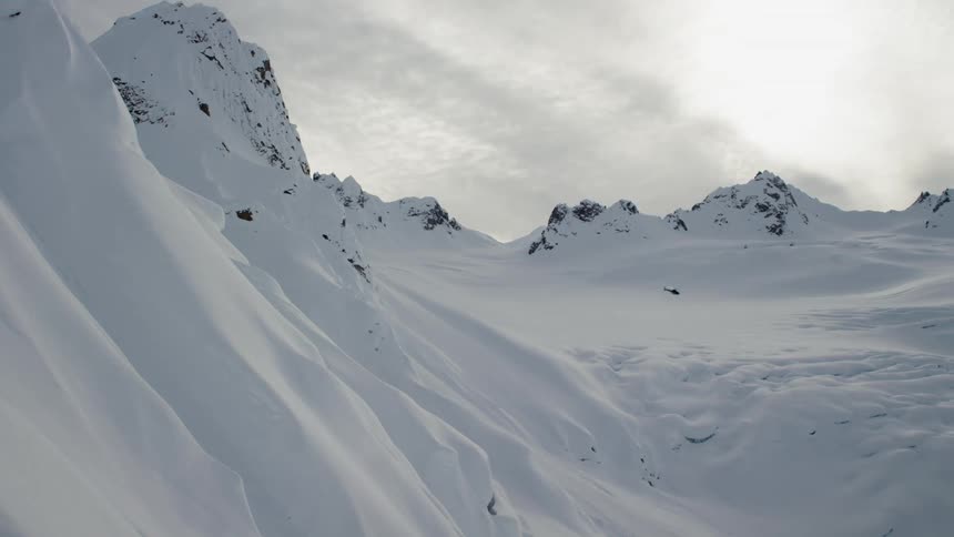 Helicopter flying through the snow covered peaks of a mountain range