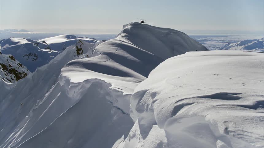 A helicopter flies and lands on a mountain