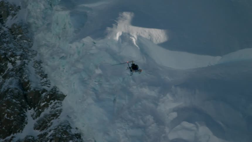 A helicopter is flying near a mountain range