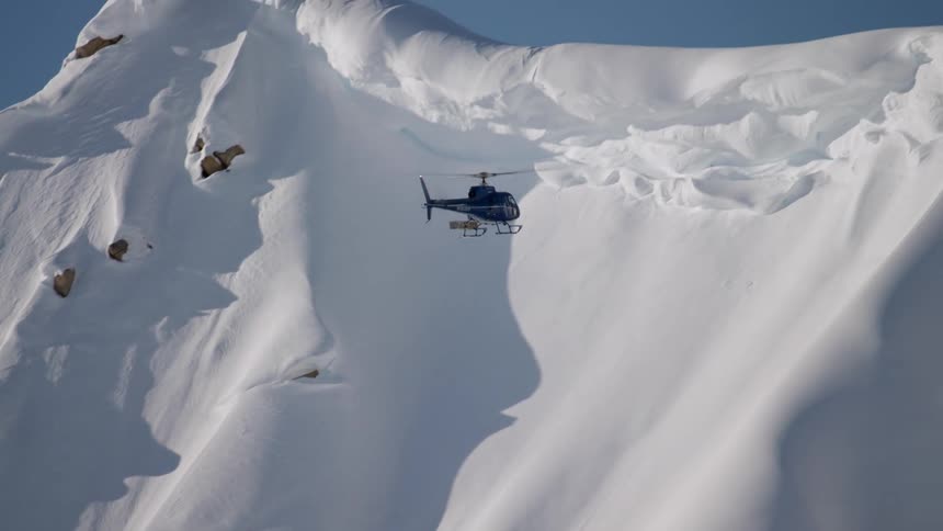A helicopter ascends to a mountain peak