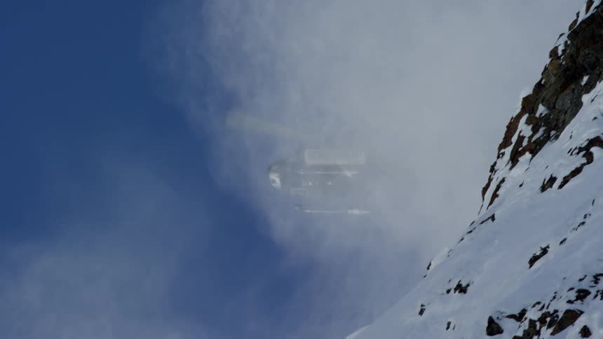 Helicopter flies over the peaks of a snow covered mountain range