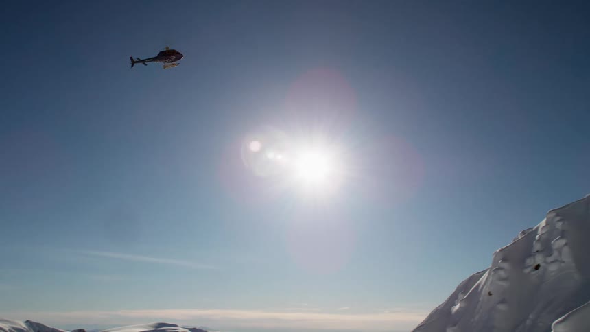 A helicopter flying over snow covered mountains