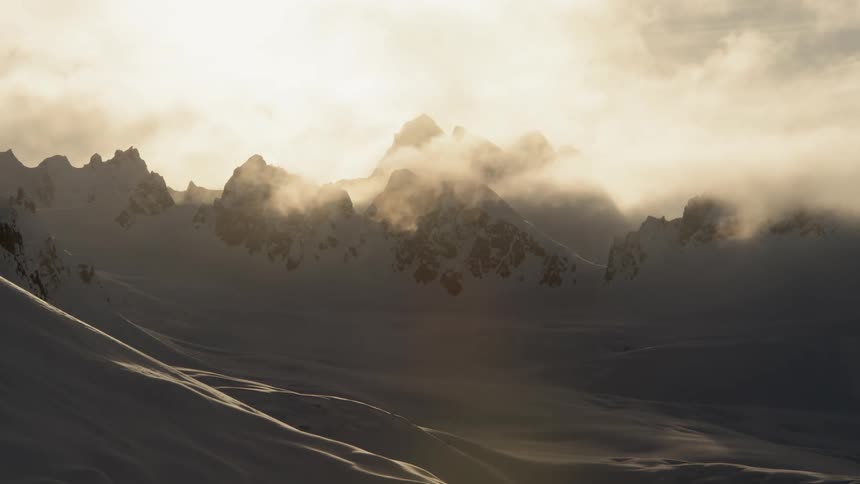 Clouds over snow covered mountain peaks