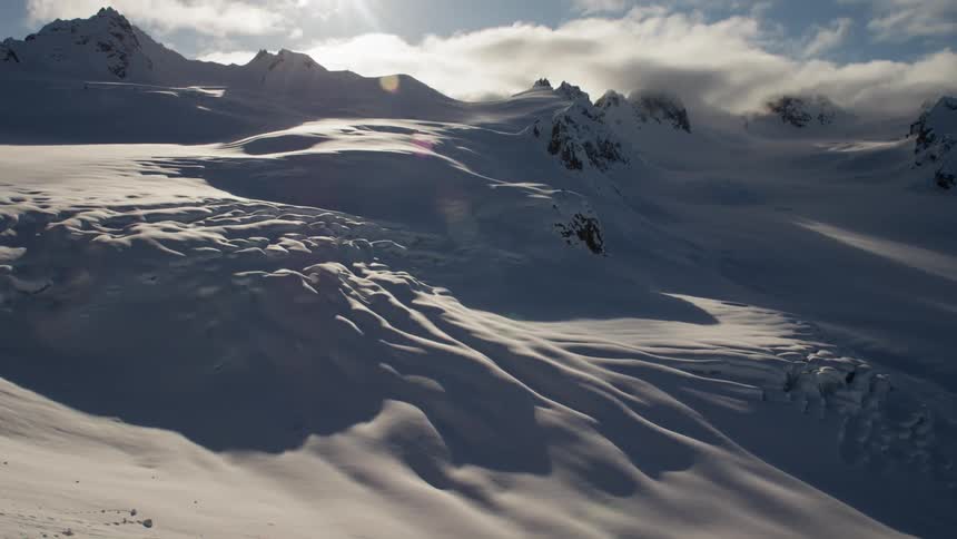 Snow covers a valley and a mountain range