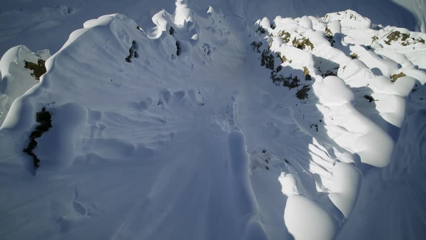 An aerial view of a mountain covered in snow is displayed