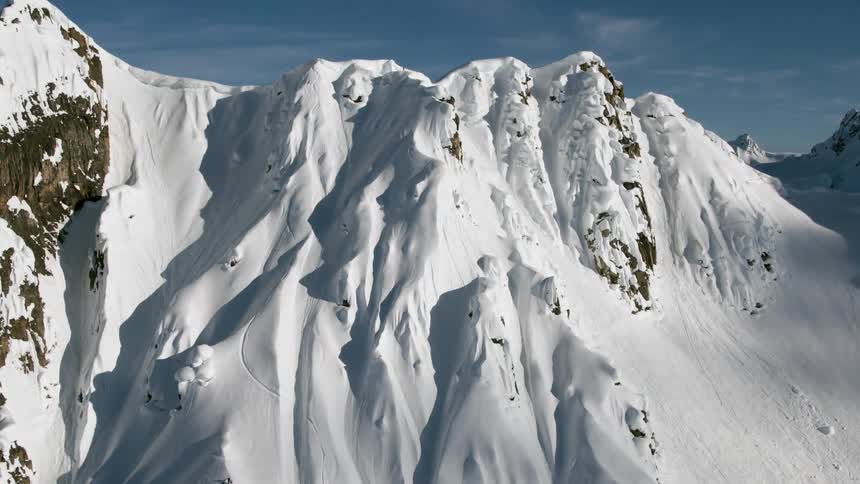A mountain range is almost completely covered in snow