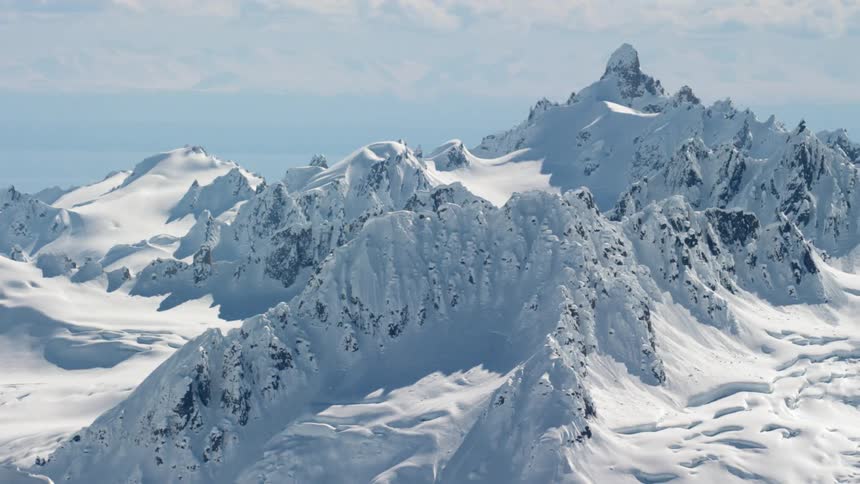 A mountain range covered in deep and drifted snow